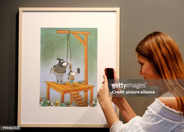 Woman takes a picture of an untitled comic illustration by Guillermo Mordillo pictured at the Ludwig Gallerie Schloss Oberhausen in Oberhausen,...