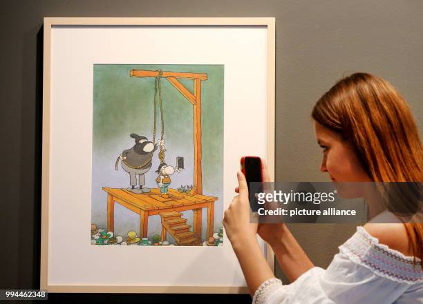 Woman takes a picture of an untitled comic illustration by Guillermo Mordillo pictured at the Ludwig Gallerie Schloss Oberhausen in Oberhausen,...