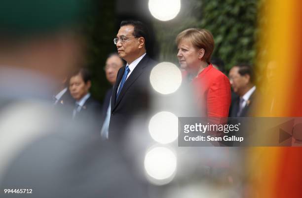 German Chancellor Angela Merkel and Chinese Premier Li Keqiang listen to a military band play their nations' respective national anthems prior to...