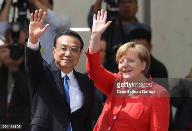 German Chancellor Angela Merkel and Chinese Premier Li Keqiang wave towards gathered supporters of the Chinese government after the two leaders...