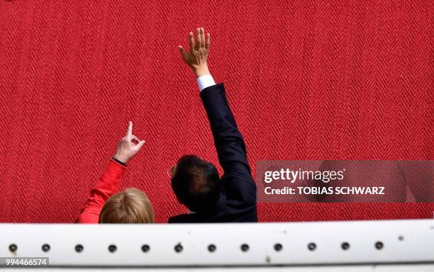 German Chancellor Angela Merkel and Chinese Premier Li Keqiang wave wellwishers after a military honor guard review during a welcoming ceremony at...