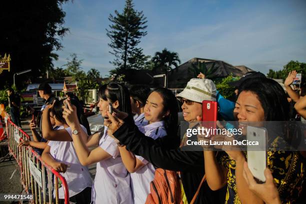 Onlookers watch and cheer as a helicopter flies towards an airstrip near Tham Luang Nang Non cave to transport the fifth boy rescued from the cave to...