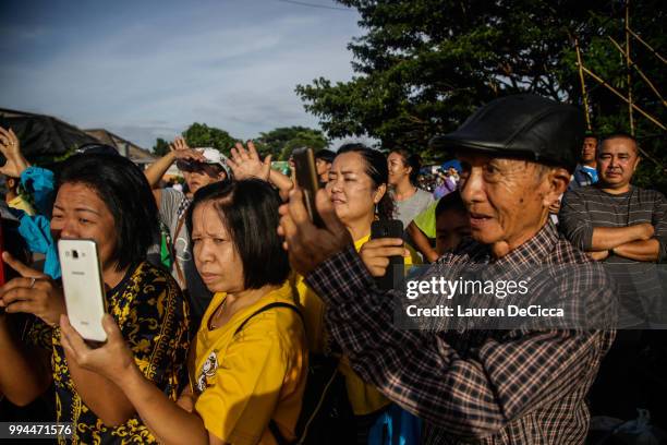 Onlookers watch and cheer as a helicopter flies towards an airstrip near Tham Luang Nang Non cave to transport the fifth boy rescued from the cave to...