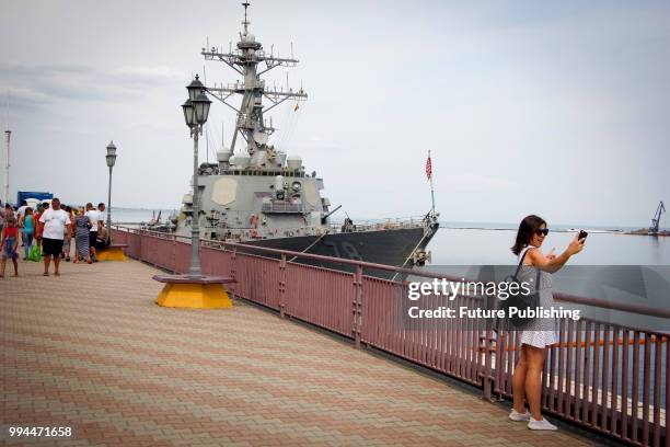 Woman takes a selfie in front of the USS Porter , an Arleigh Burke-class destroyer of the United States Navy, at the Maritime Terminal, Odesa,...