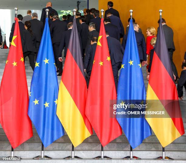 Ministers and delegation members leave behind the Chinese, European and German flags) after posing for a group photo with the German Chancellor and...