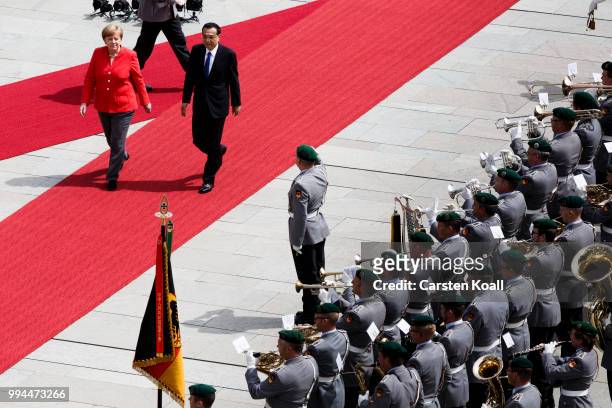German Chancellor Angela Merkel and Chinese Premier Li Keqiang walk among the honor guard during the welcome ceremony at the Chancellery on July 9,...
