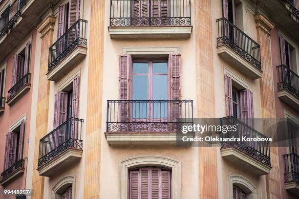 intricate iron work balconies, wooden shutters and sculptural building details on the narrow streets of barcelona, spain. - calle stockfoto's en -beelden