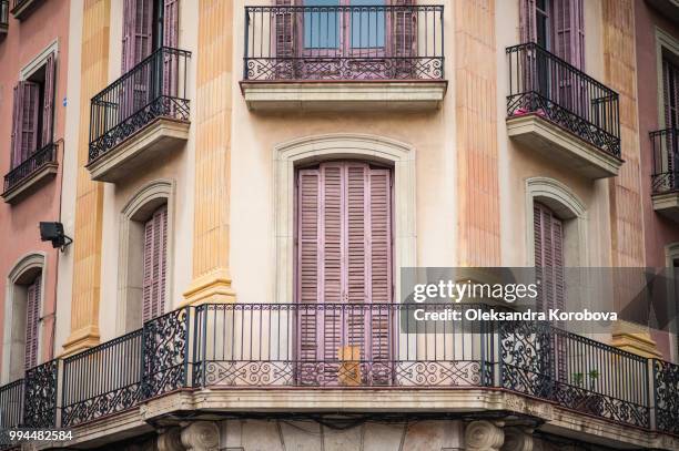 intricate iron work balconies, wooden shutters and sculptural building details on the narrow streets of barcelona, spain. - calle urbana imagens e fotografias de stock