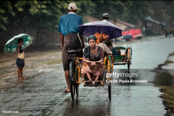 Rohingya woman travels by rickshaw during heavy monsoon rains heading to her home inside an IDP camp outside of Sittwe, Myanmar on June 7, 2014."n