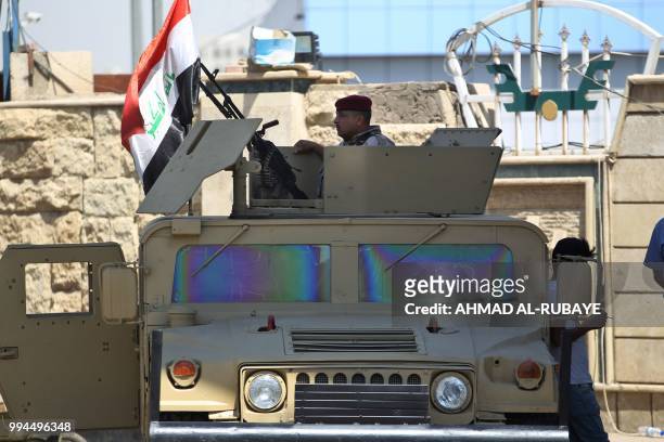 Member of the Iraqi security forces mans a turret in a humvee outside a warehouse where ballots from the May parliamentary election are stored in the...