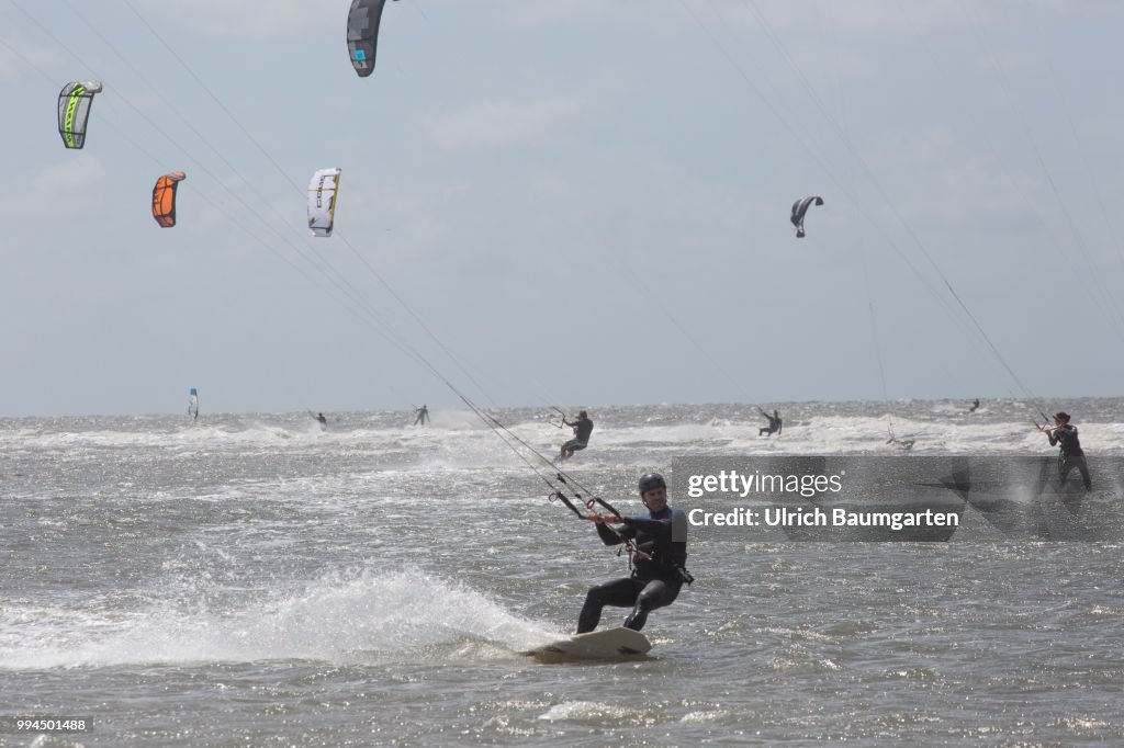 Trendsport kite surfing on the North sea coast in St. Peter Ording and the problem of bird protection.