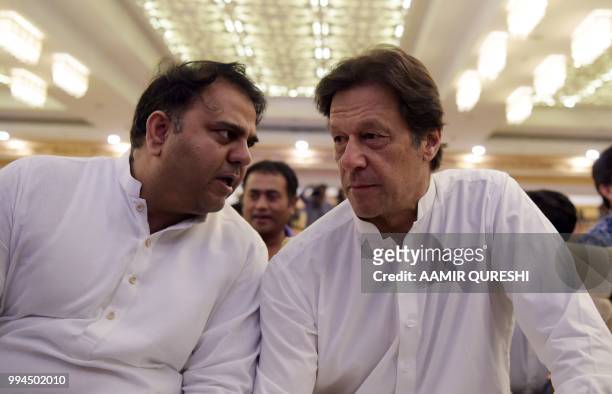 Pakistani cricketer-turned-politician and head of the Pakistan Tehreek-i-Insaf Imran Khan speaks with his party spokesperson Fawad Chaudhry before...