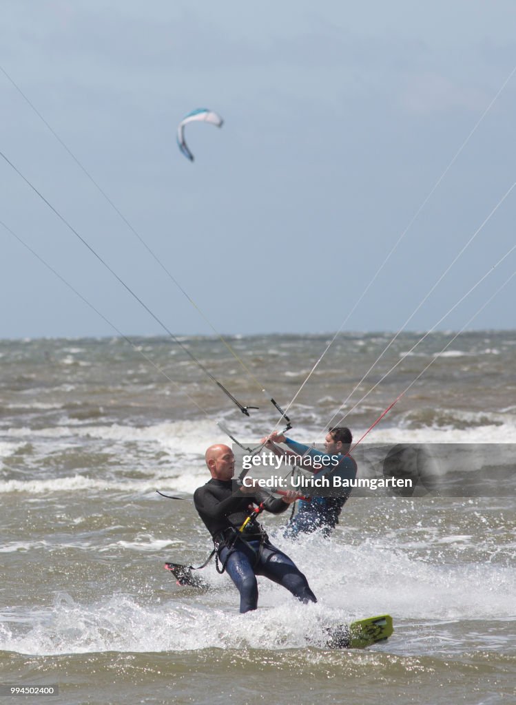 Trendsport kite surfing on the North sea coast in St. Peter Ording and the problem of bird protection.