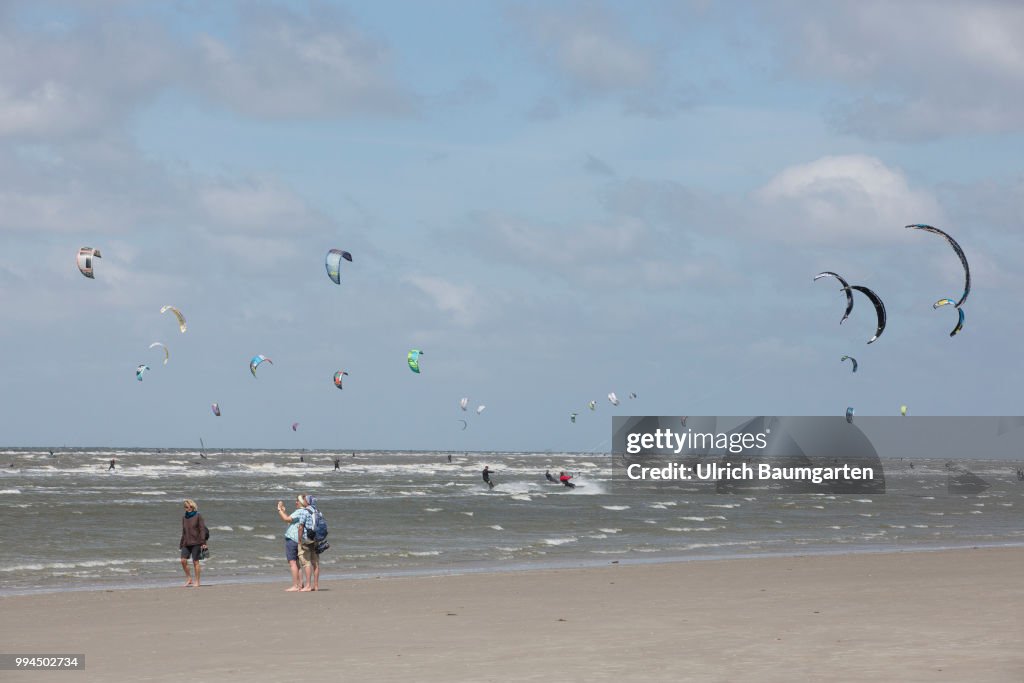 Trendsport kite surfing on the North sea coast in St. Peter Ording and the problem of bird protection.