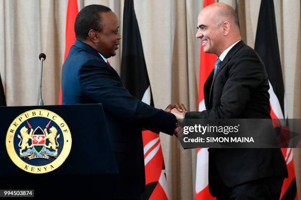 Swiss President Alain Berset shakes hands with his Kenyan counterpart President Uhuru Kenyatta during a joint press conference at the State House in...