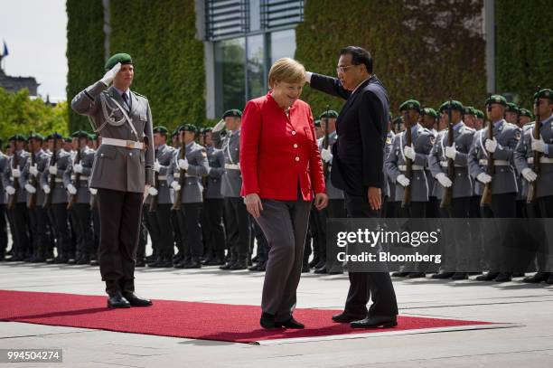 Angela Merkel, Germany's chancellor, center, reacts while reviewing an honor guard with Li Keqiang, China's premier, at the Chancellery building in...