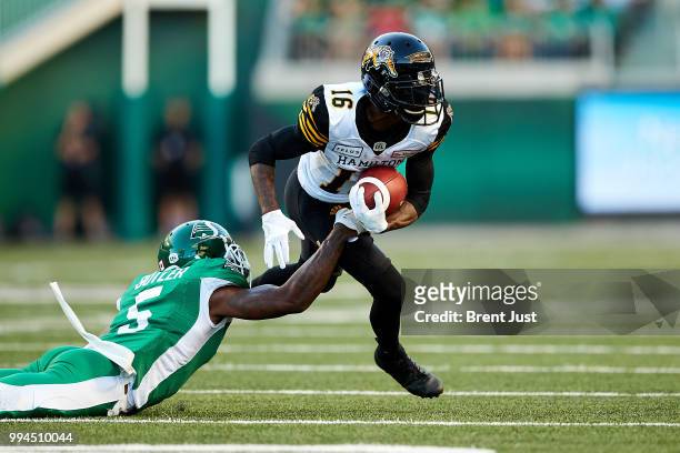 Brandon Banks of the Hamilton Tiger-Cats gets around a diving Crezdon Butler of the Saskatchewan Roughriders in the game between the Hamilton...