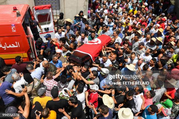 Mourners carry the coffin of killed Tunisian police officer Sgt. Arbi Guizani during a funerary procession in the capital Tunis' northwestern suburb...