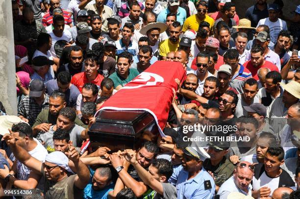 Mourners carry the coffin of killed Tunisian police officer Sgt. Arbi Guizani during a funerary procession in the capital Tunis' northwestern suburb...