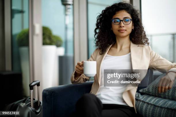 businesswoman relaxing at a hotel's cafe - damircudic stock pictures, royalty-free photos & images