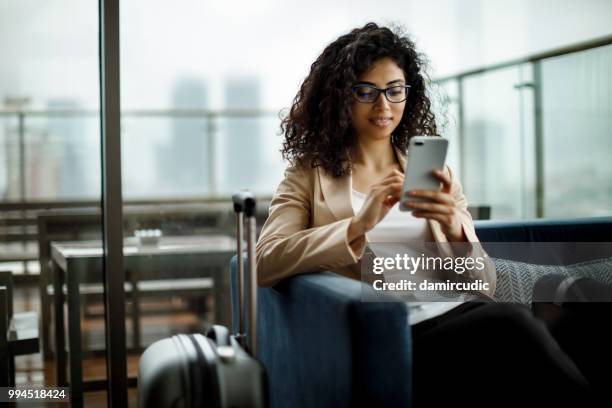 young businesswoman using mobile phone - airport imagens e fotografias de stock