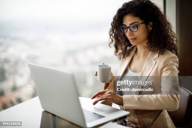 young businesswoman using laptop at a cafe - damircudic stock pictures, royalty-free photos & images