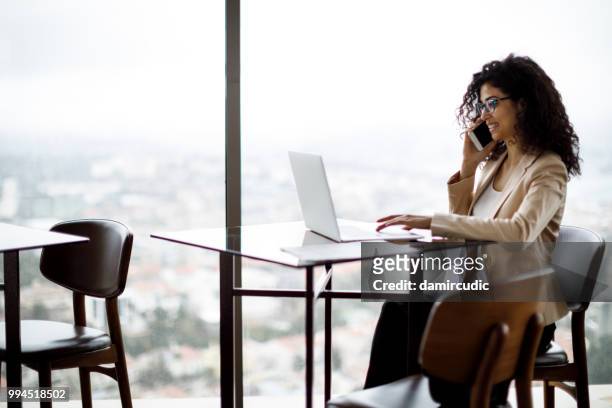 young businesswoman working on laptop at a cafe - damircudic stock pictures, royalty-free photos & images
