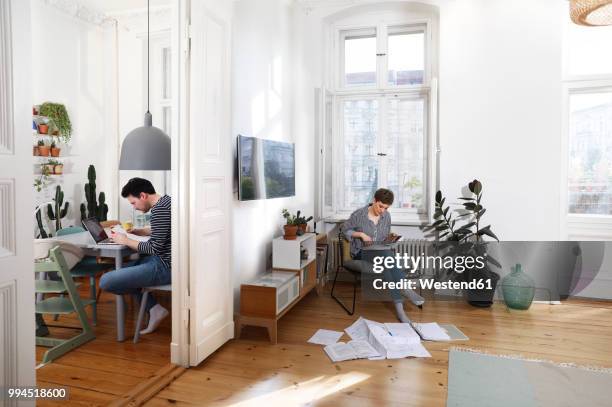 couple sitting at home, sorting files with documents - pareja de mediana edad fotografías e imágenes de stock