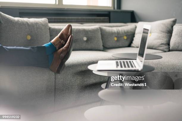 businessman's feet on couch next to laptop - pause stock-fotos und bilder