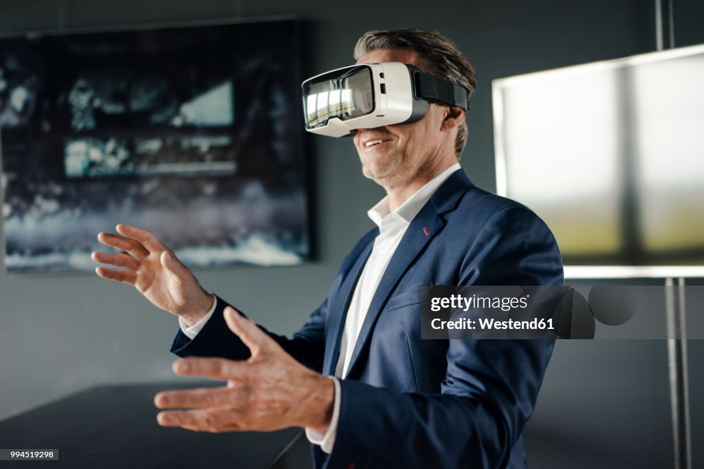 Mature businessman wearing VR glasses in office