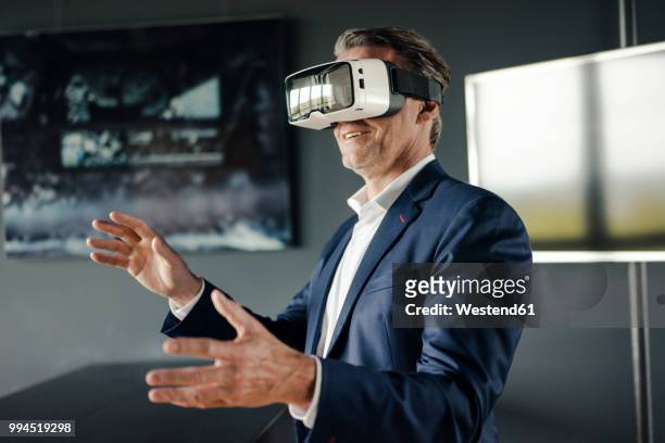 mature businessman wearing vr glasses in office - 2018 glasses ストックフォトと画像