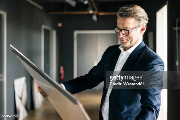 mature businessman in office looking at painting - kunsthändler stock-fotos und bilder