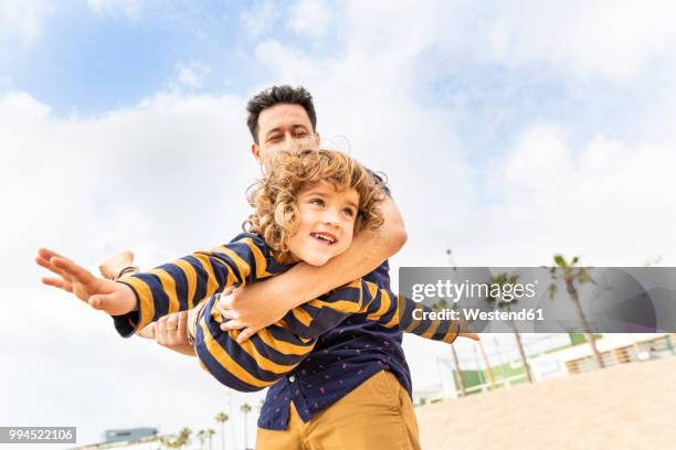 spain, barcelona, father and son playing on the beach - 飛行機のまね ストックフォトと画像