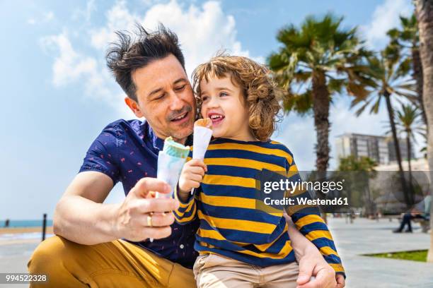 spain, barcelona, father and son enjoying an ice cream at seaside - barcelona free stock-fotos und bilder
