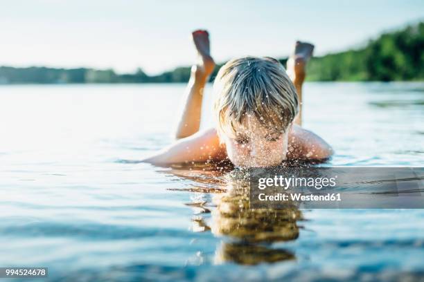 boy in a lake blowing into water - saksen stockfoto's en -beelden