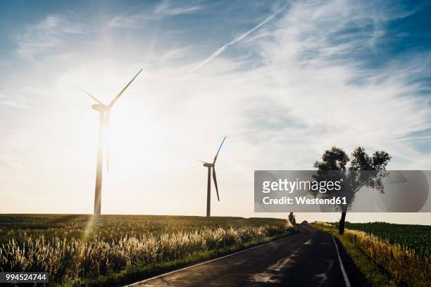 empty country road and wind turbines at sunset - saksen stockfoto's en -beelden