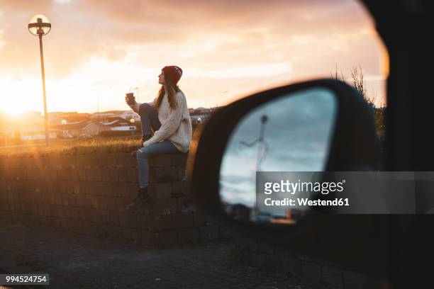 iceland, young woman with coffee to go at sunset, wing mirror - sitting in car stock pictures, royalty-free photos & images