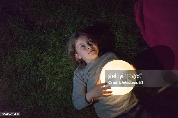 girl lying on meadow, holding moon - only kids at sky stock pictures, royalty-free photos & images