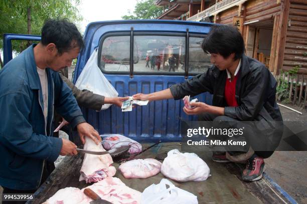 Buying and selling meat from the back of a van at Lugu Lake, Yunnan, China. Lugu Lake is located in the North West Yunnan plateau in the centre of...