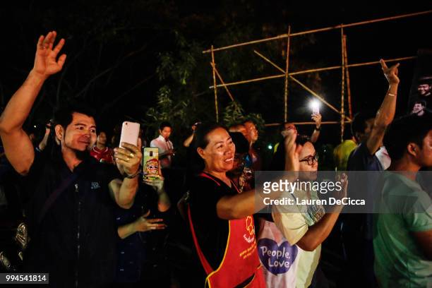 Onlookers watch and cheer as ambulances transport some of the rescued schoolboys from a helipad to a hospital on July 9, 2018 in Chiang Rai,...
