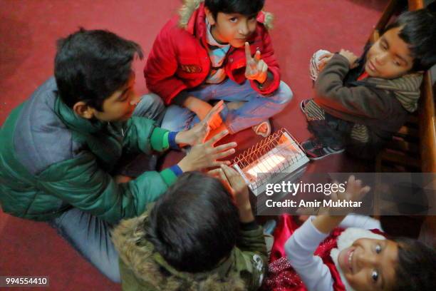 pakistani christian family (children) sitting near electric heater in winters and celebrating christmas 2017 - amir mukhtar stock pictures, royalty-free photos & images