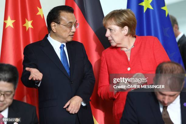 German Chancellor Angela Merkel and Chinese Premier Li Keqiang talk as State Minister Niels Annen and deputy Foreign Minister Le Yucheng sign a...