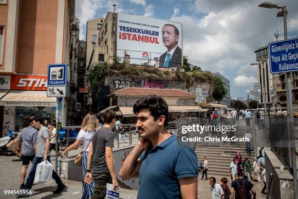 People walk past a poster showing the portrait of Turkey's President Recep Tayyip Erdogan and the words translating to "Thank you Istanbul" on July...