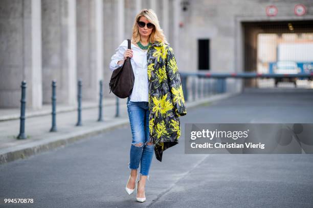 Gitta Banko wearing a floral patterned coat by Steffen Schraut, white off-shoulder blouse with asymmetrical cut by Balossa, brown suede bag by Amma...