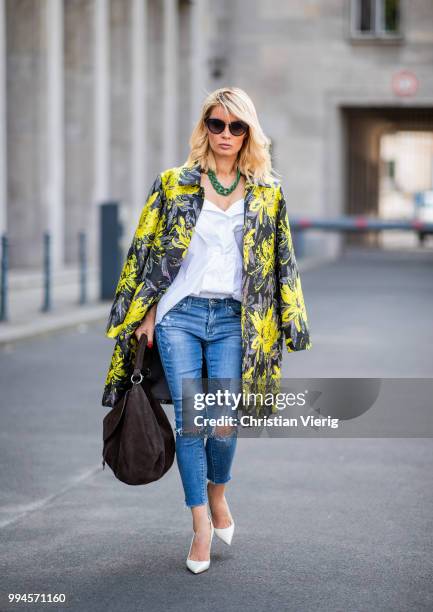 Gitta Banko wearing a floral patterned coat by Steffen Schraut, white off-shoulder blouse with asymmetrical cut by Balossa, brown suede bag by Amma...