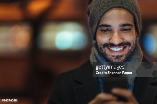 young man using smartphone on city street at night - smartphone lesen nacht stock-fotos und bilder