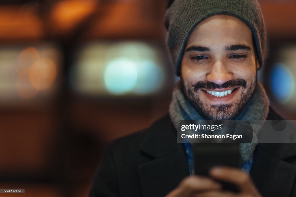 Young man using smartphone on city street at night