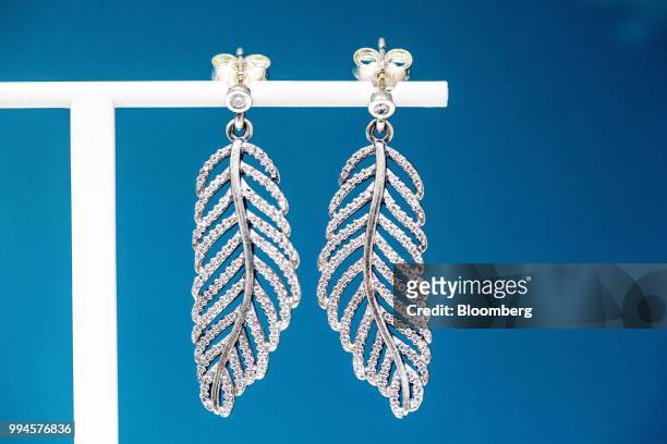Shimmering feather earrings hang on display inside a Pandora AS store in Copenhagen, Denmark, on Monday, July 9, 2018. Pandora designs, manufactures,...