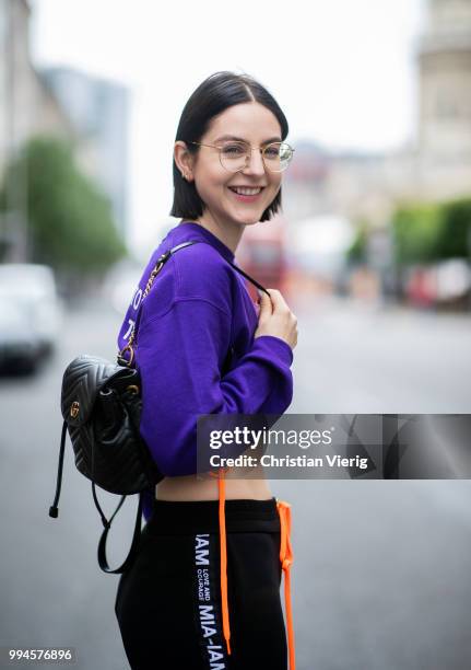 Maria Barteczko wearing purple printed croped sweater MIAM-IAM, black logo track pants MIA-IAM, black sock boots Stuart Weitzman, black leather...