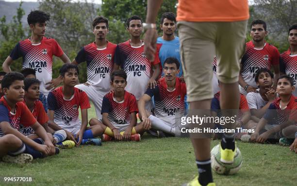 Members of the M2M football club listen to their coach during a practice session in a park at Ghamroj Village on June 27, 2018 near Gurugram, India....